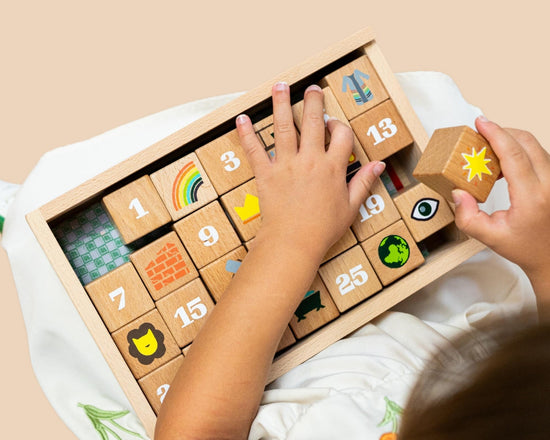 Child playing with a wooden number Advent Block set on a beige background